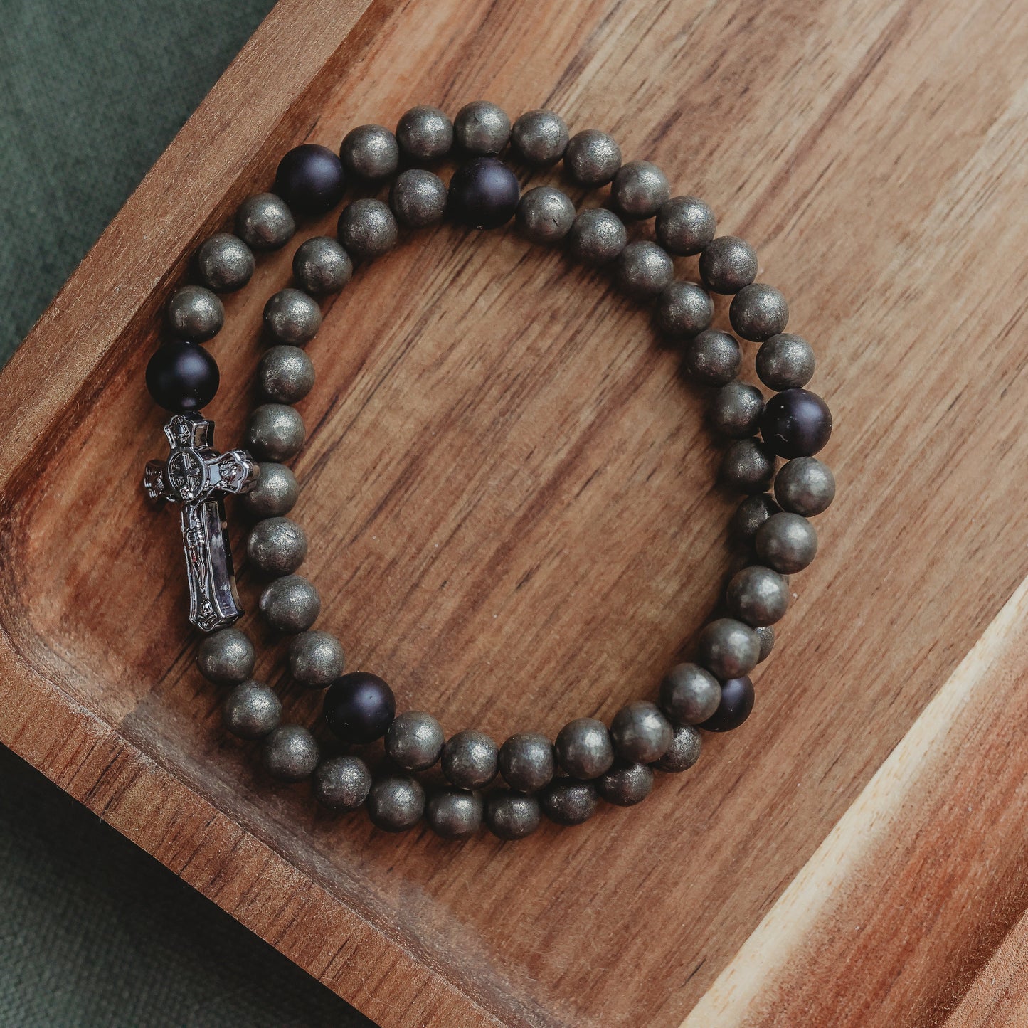 Beaded bracelet with a cross on a wooden tray