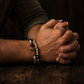 Praying hands with a bracelet on a wooden surface